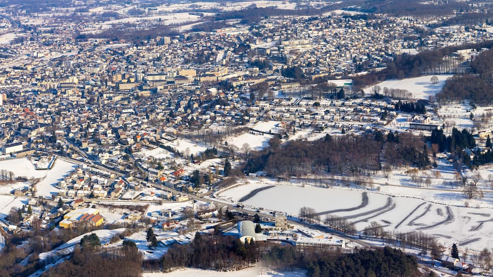 Une ville enneigée, avec une rivière, des bâtiments et un grand espace ouvert.