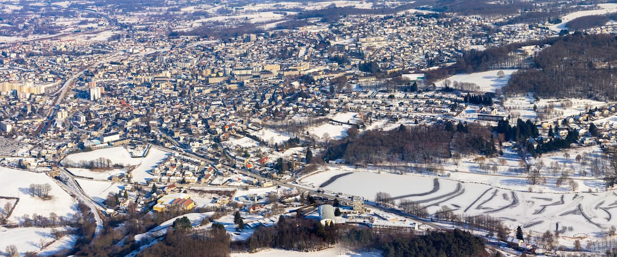 A snow-covered town with a river, buildings, and a large open field.