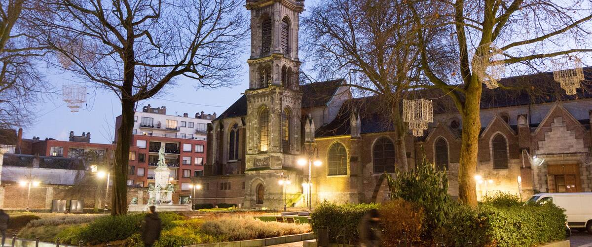 A historic church with a tall tower and a statue in the courtyard.