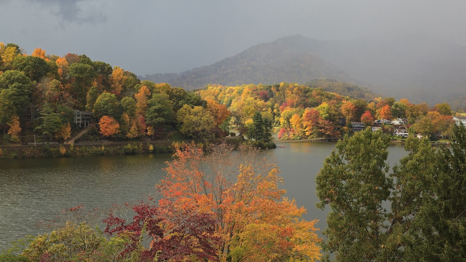 A lake surrounded by autumn-colored trees and a mountain in the background.