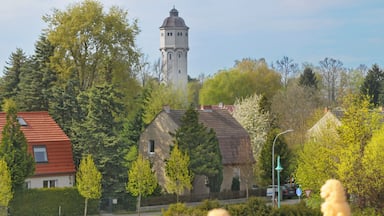 Una torre, casas, árboles y una estatua.