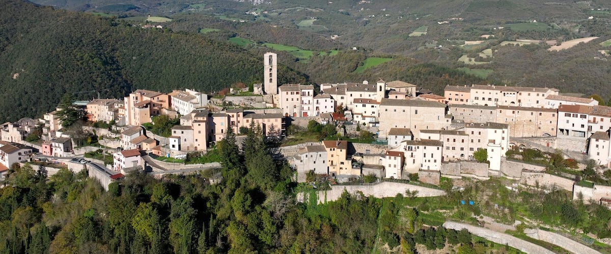 A mountainous village with historic buildings and a prominent church tower.