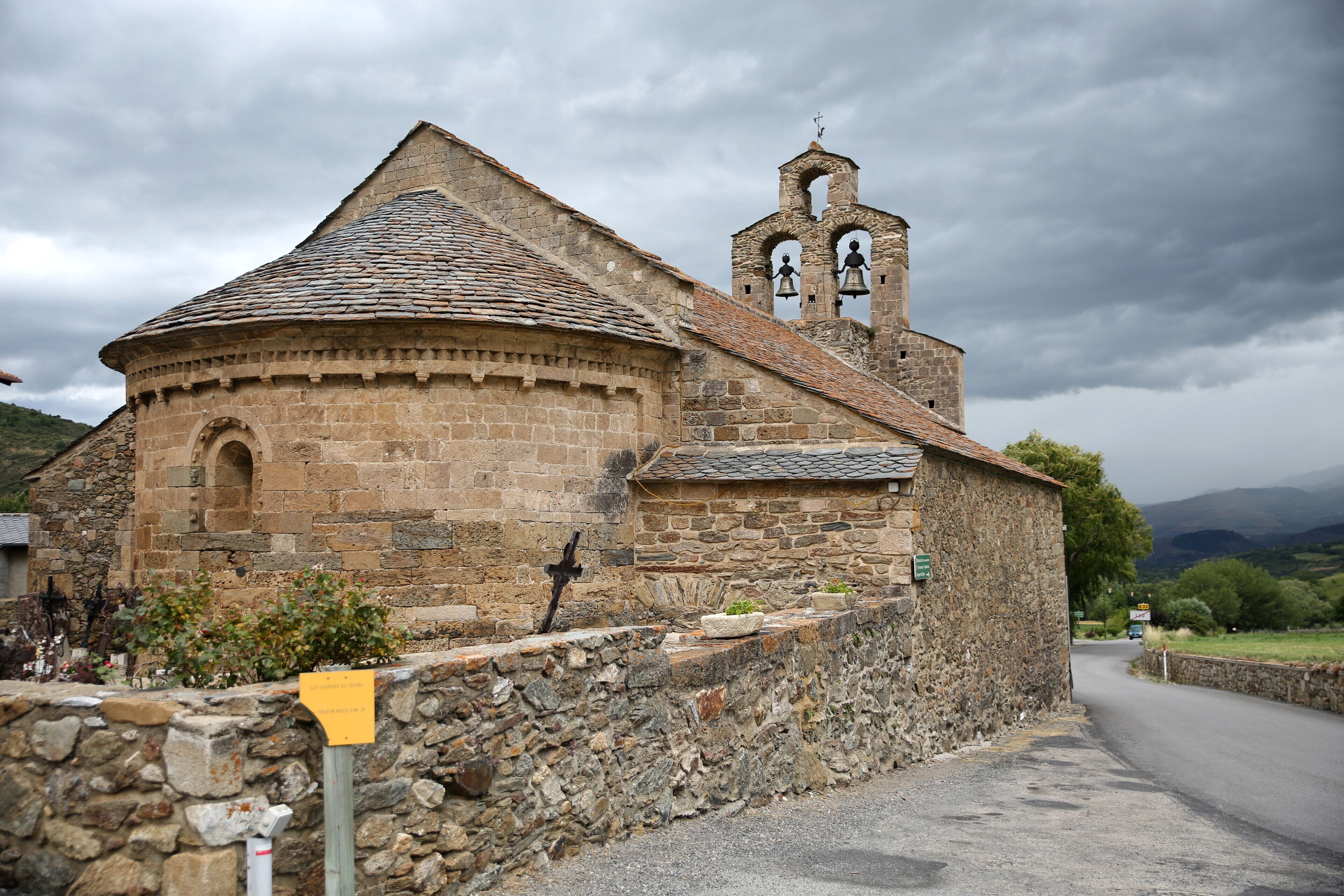 A stone church with a bell tower and a circular apse.