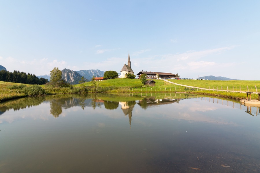 Inzell, Germany - August 5, 2018: View of the Nikolauskirche church in the Bavarian community of Inzell with the Alps in the background.