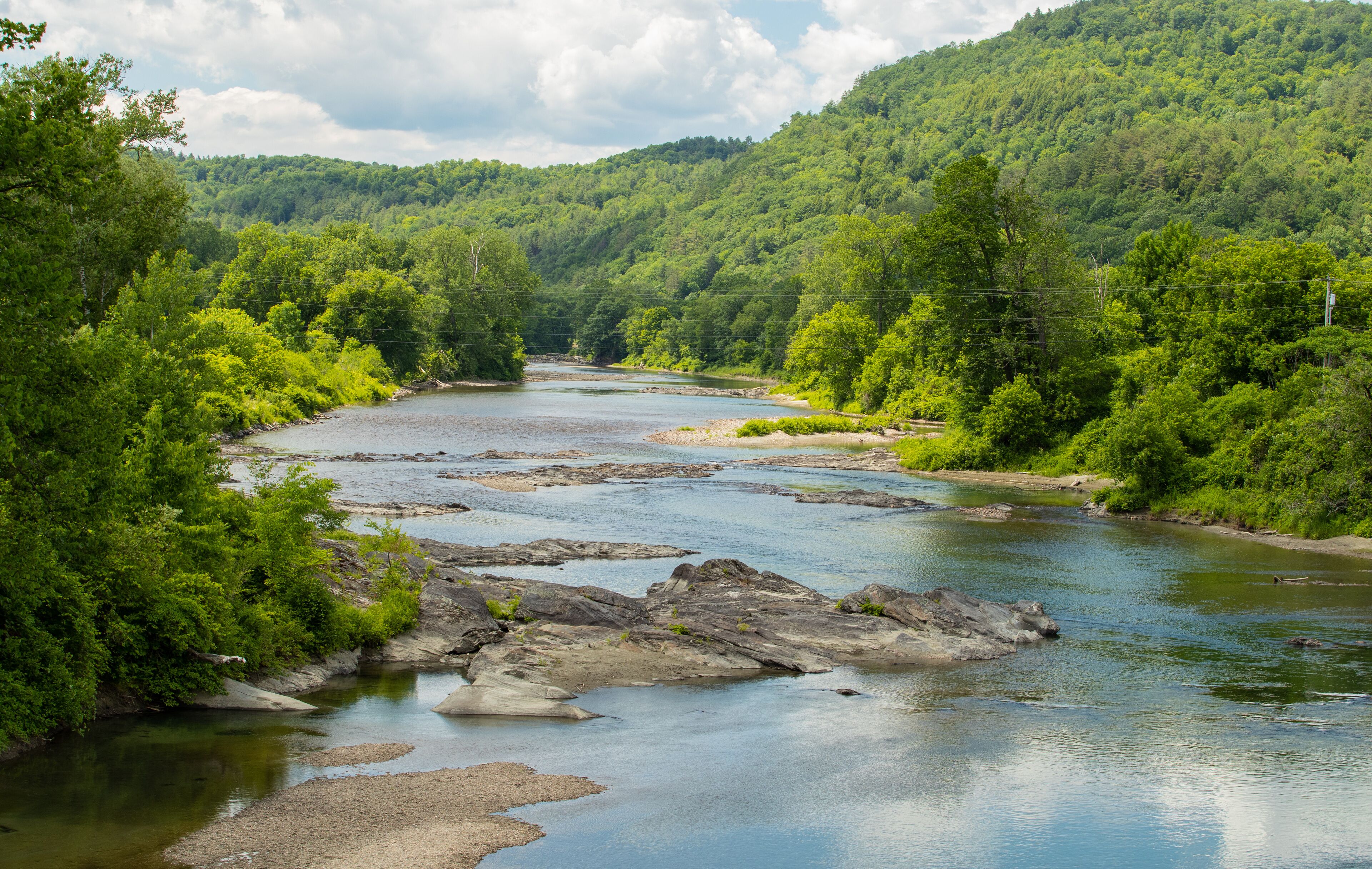 A river flowing through a forested valley with rocky outcrops and dense greenery.