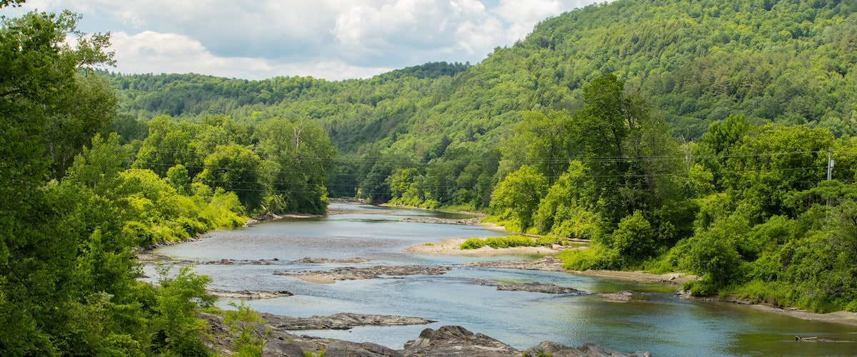 A river flowing through a forested valley with rocky outcrops and dense greenery.