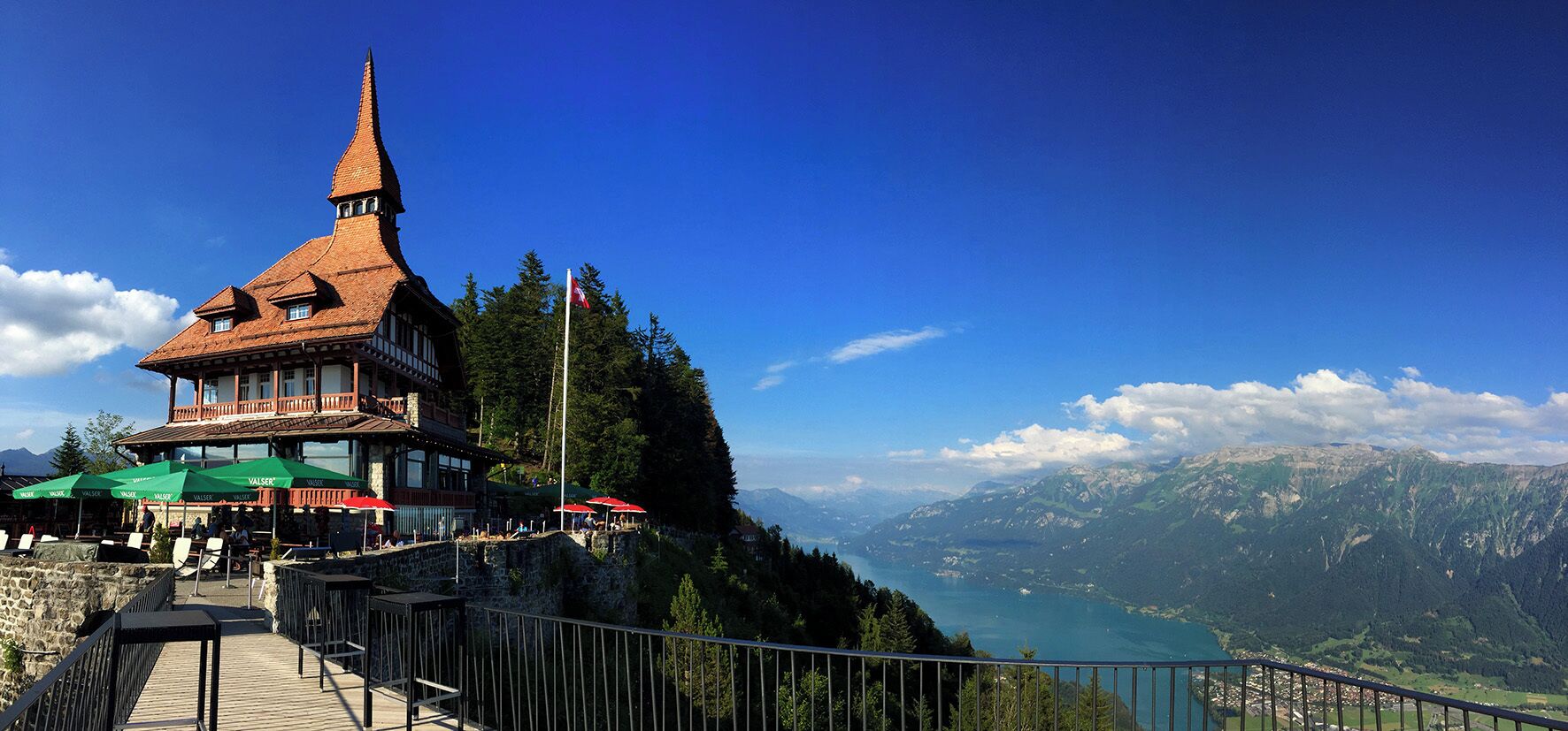 A mountain lodge with a steep roof and a tall tower, overlooking a valley and lake.