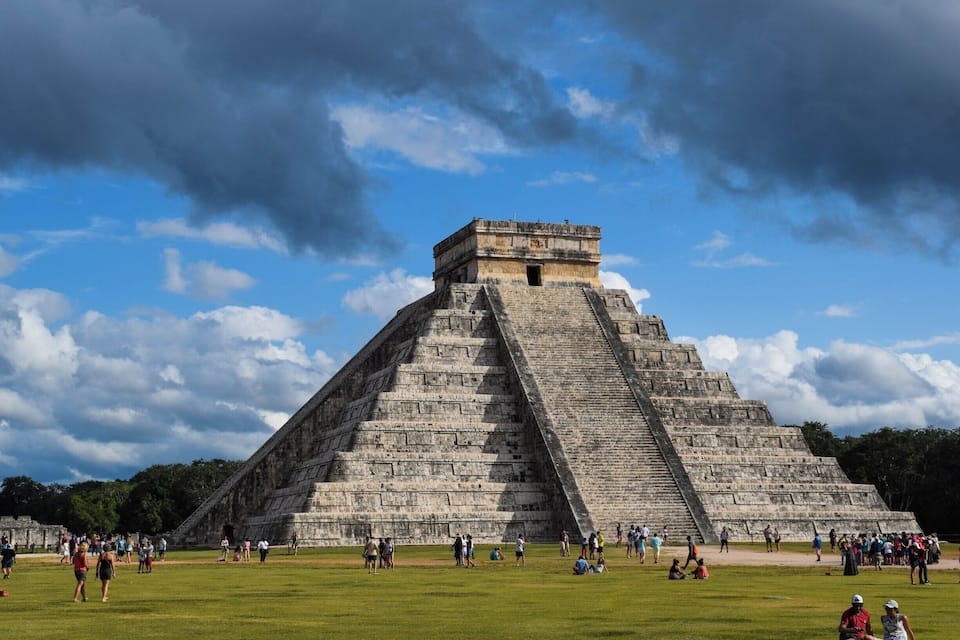 A large pyramid with tourists around it.