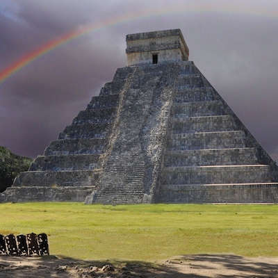 Une grande pyramide de pierre avec un arc-en-ciel dans le ciel.