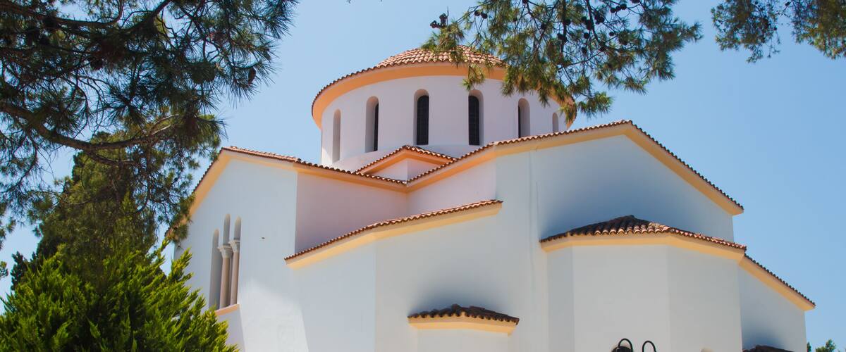 A white building with a tiled roof and arched windows.