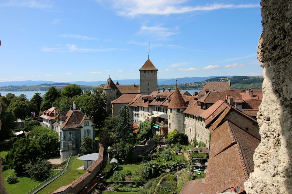 A historic town with a prominent tower, terraced houses, and a lush green park.