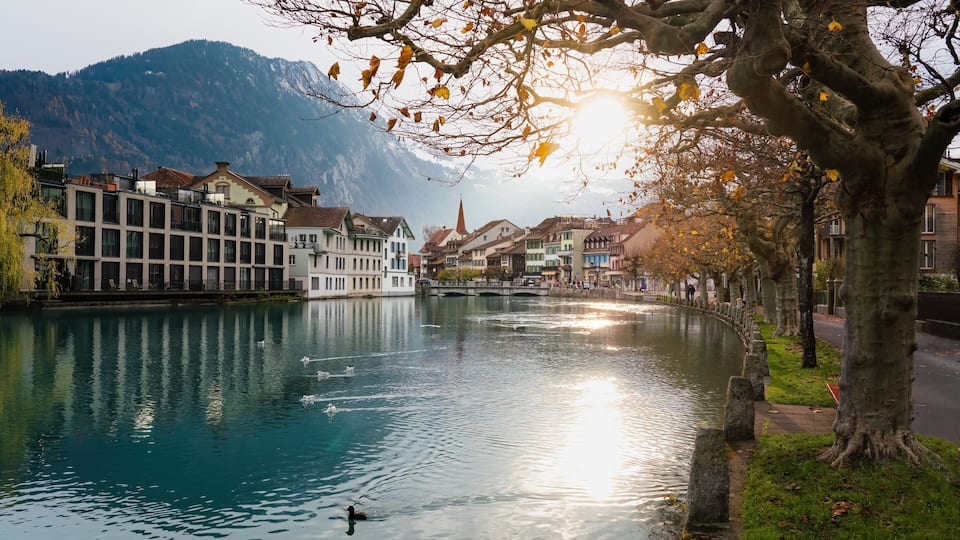 A calm river with buildings and a mountain in the background.