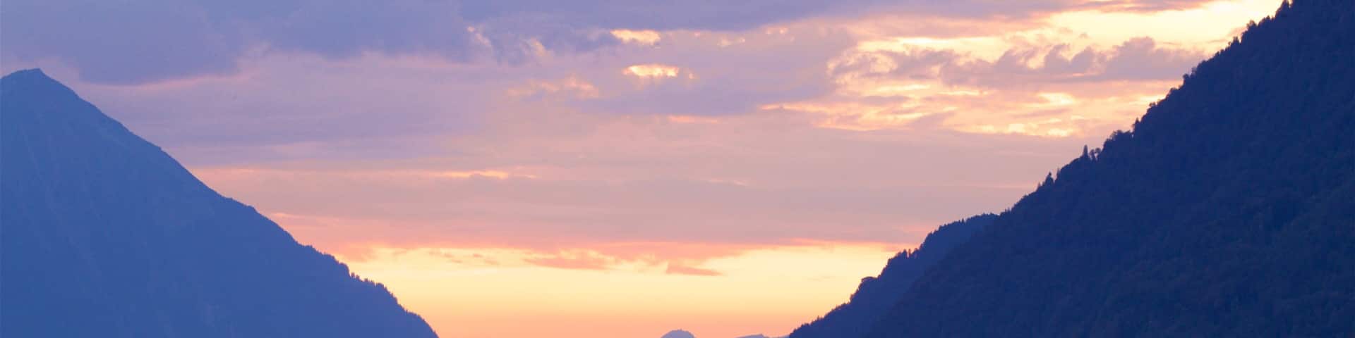 Interlaken which includes a lake or waterhole, a sunset and mountains