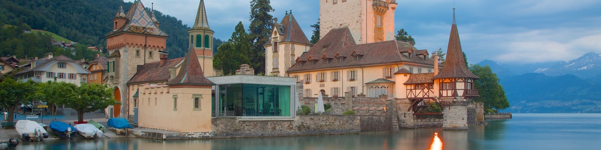 A historic castle by a calm lake with boats docked nearby.