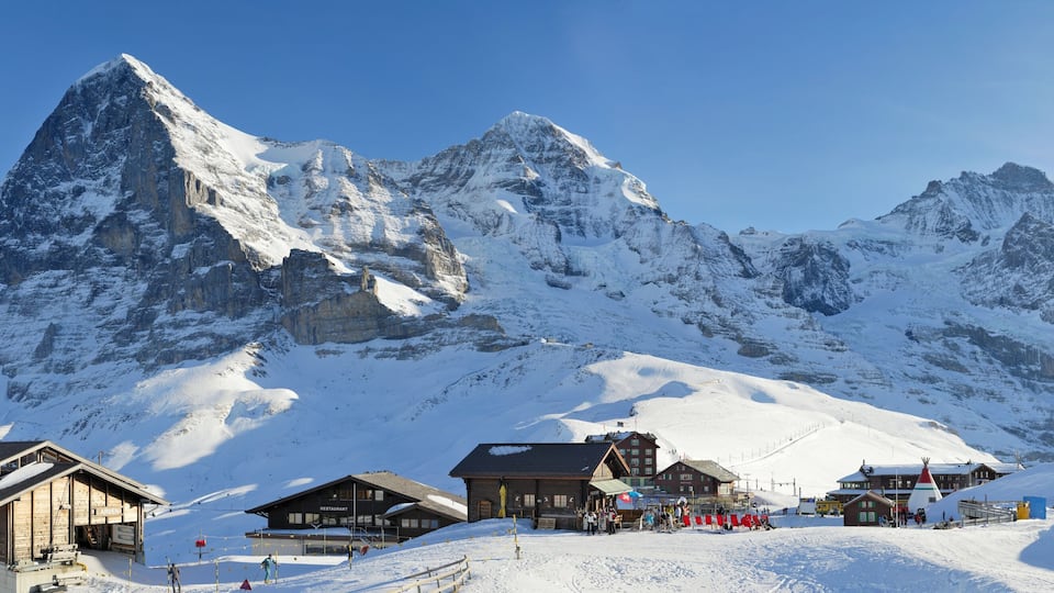 A snow-covered mountain with a ski resort and wooden buildings.