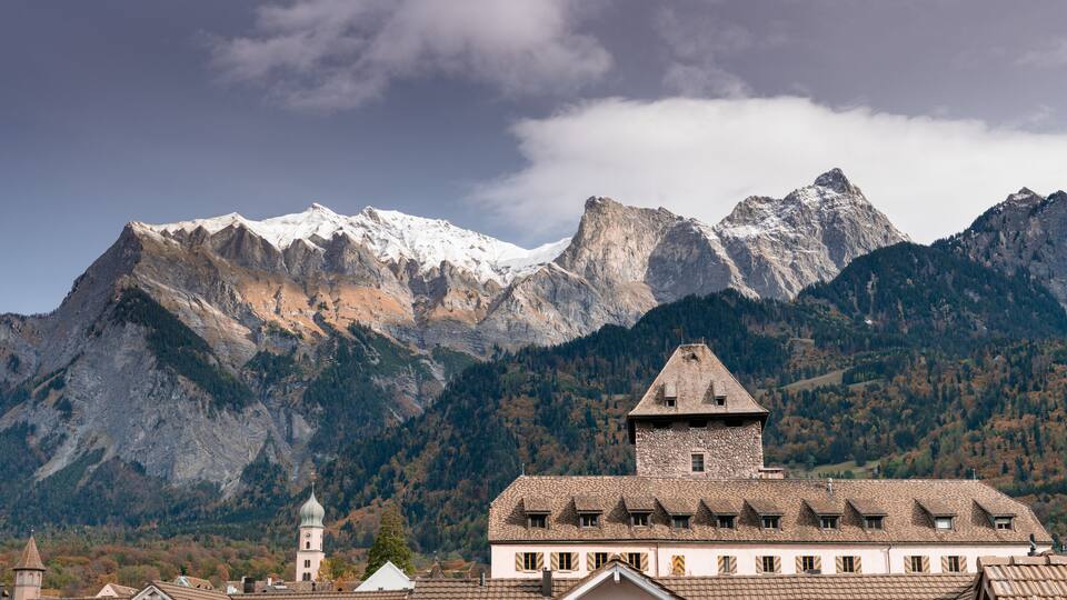 A mountain range with a church and a stone tower in the foreground.