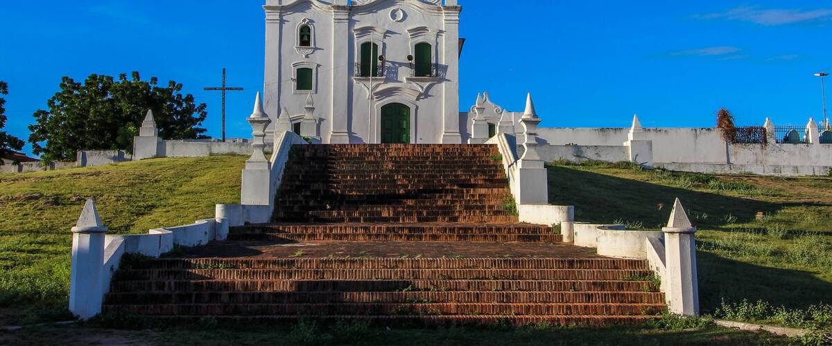 A white church with a green door and a cross on the wall.
