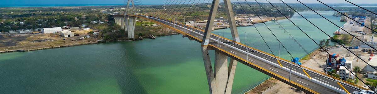 A cable-stayed bridge spanning a river with a clear sky and distant landscape.