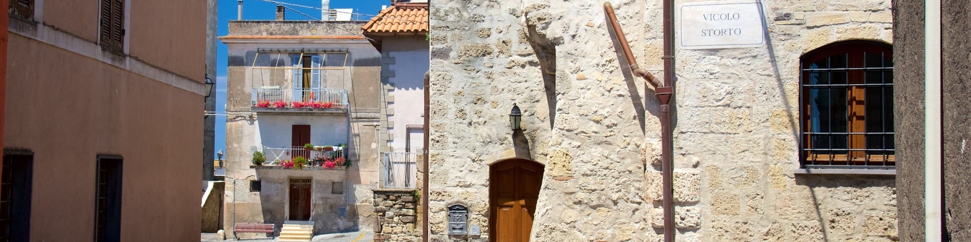 A narrow street with stone buildings, a sign reading "VICOLO STORTO", and a wooden door.