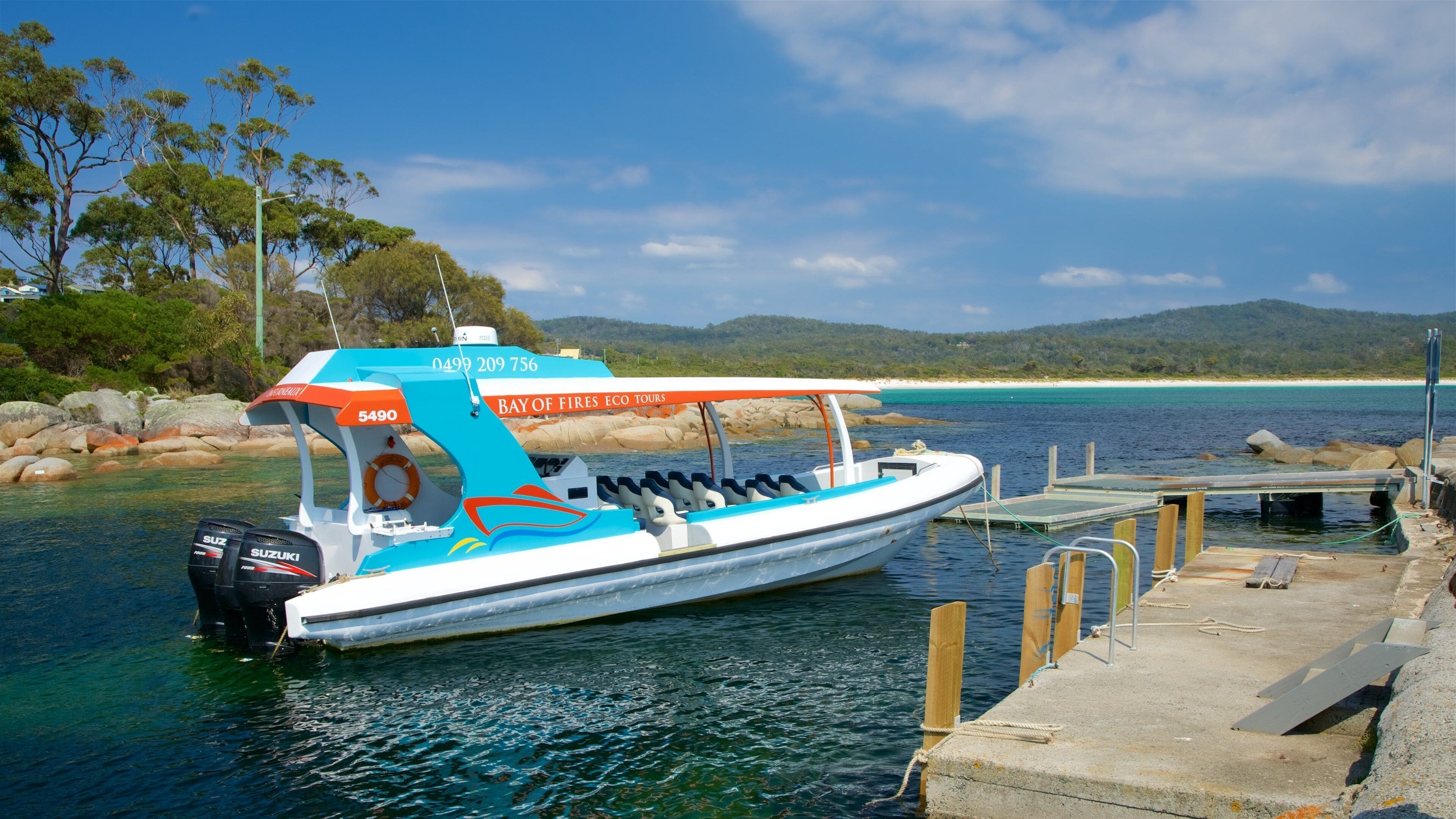A boat docked at a pier with a clear view of the bay and surrounding landscape.