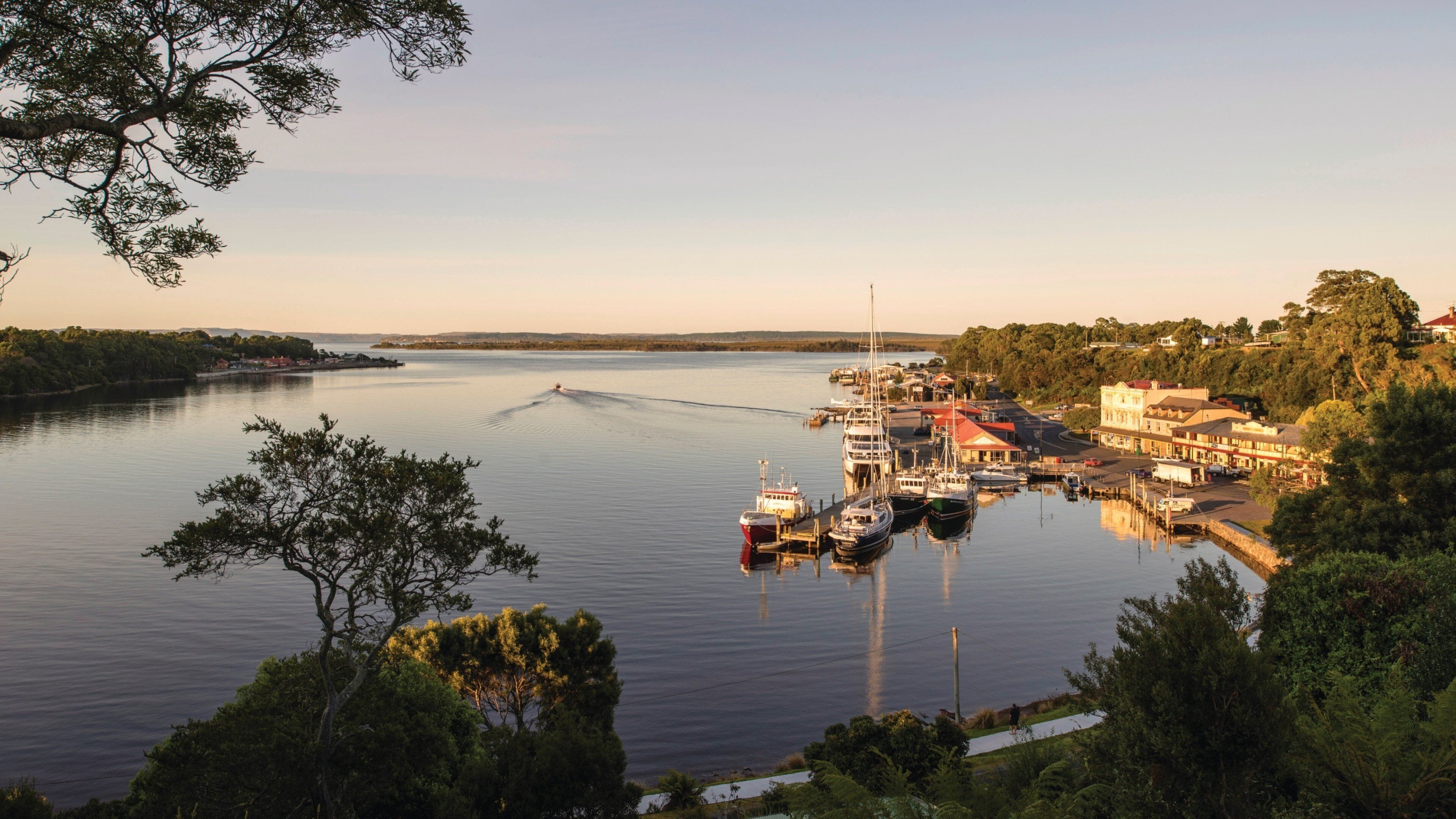 Tasmanias vestkyst som viser solnedgang, bukt eller havn og landskap