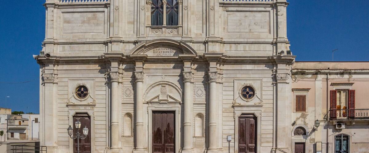 A historic building with a symmetrical facade, large wooden doors, and arched windows.