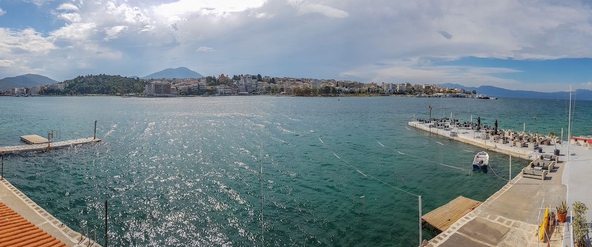 A coastal cityscape with a marina, clear blue waters, and a mountain in the background.