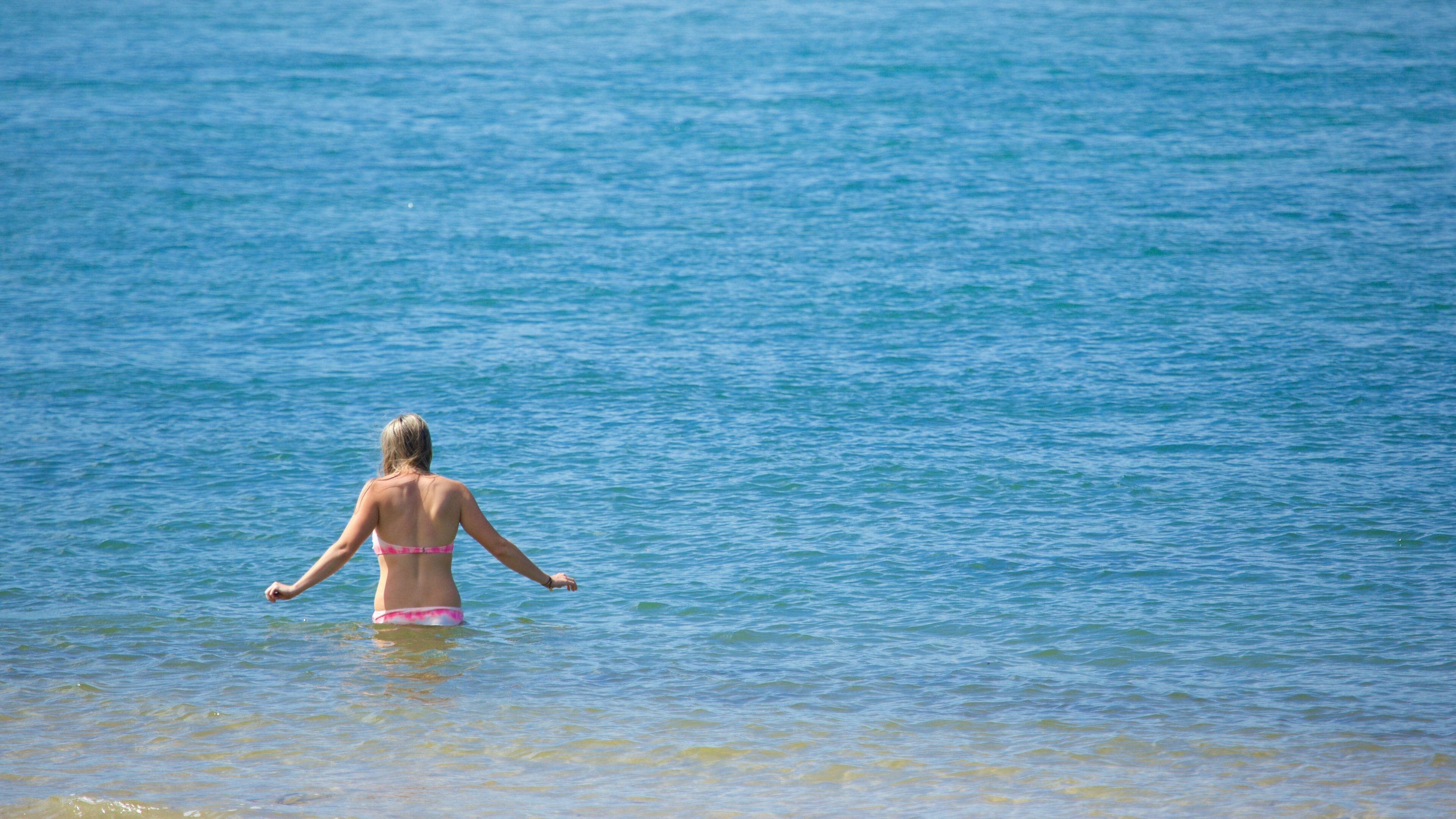 A person in a bikini standing in shallow water.