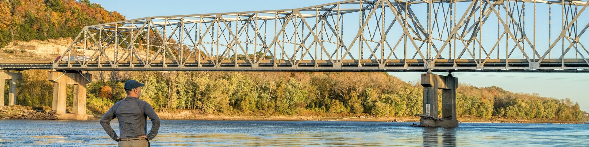 Lonely male figure at the old boat ramp on Missouri River at Taylor's Landing near Rocheport, MO, fall colors scenery with the bridge view