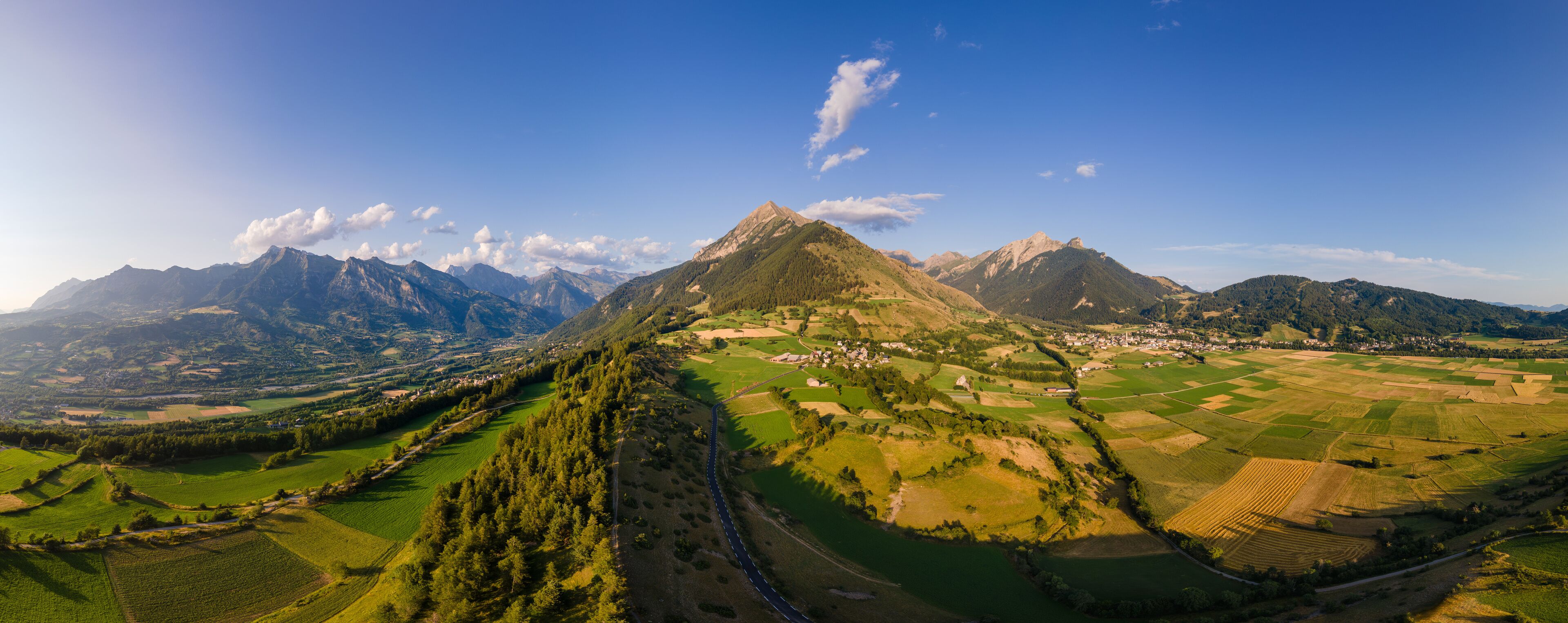 A mountainous landscape with a prominent peak, green fields, and a small village.