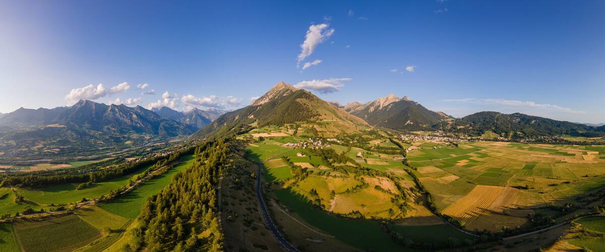 A mountainous landscape with a prominent peak, green fields, and a small village.