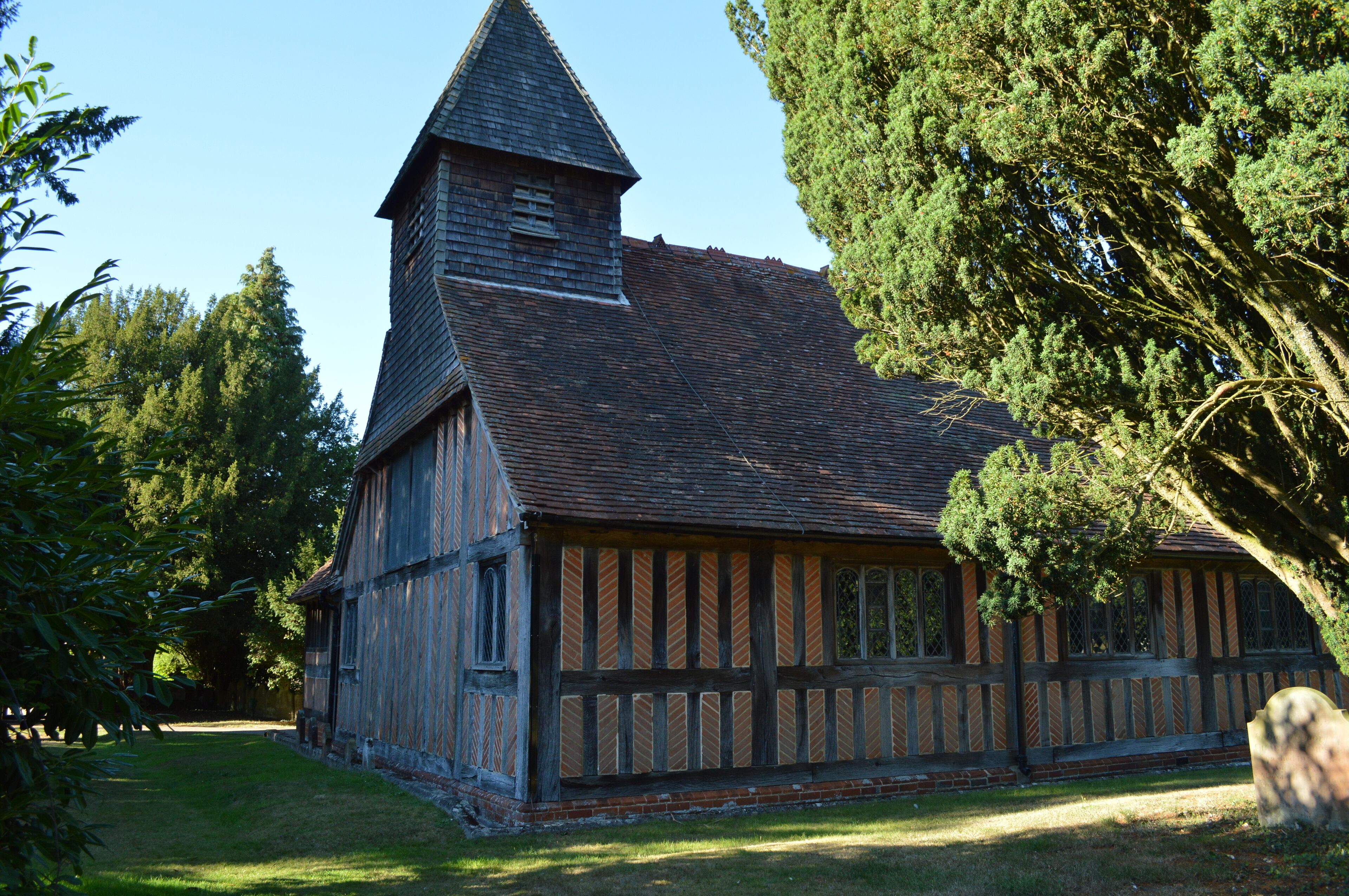 A historic timber-framed building with a steeply pitched roof and a prominent tower.