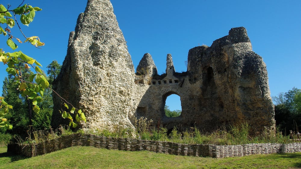 A stone ruin with a large archway and a tall, pointed structure.