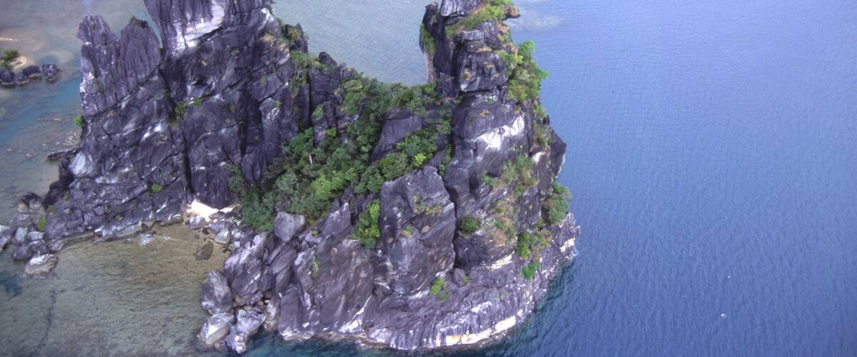 An aerial view of a rocky island with clear blue waters.