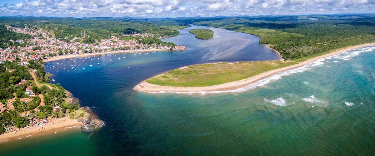 An aerial view of a coastal town with a bay, a river, and surrounding greenery.