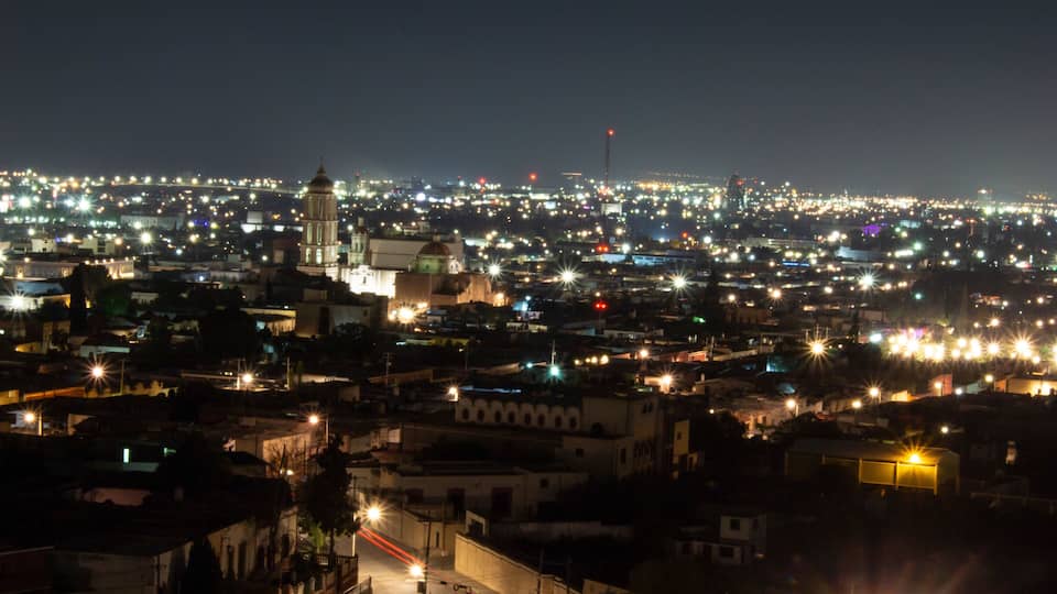 A cityscape at night with illuminated buildings and a prominent tower.