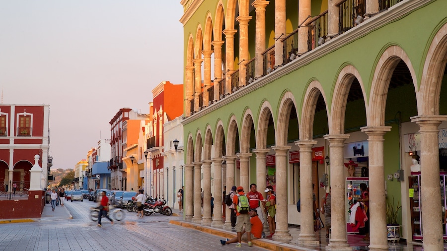 Una calle bordeada de edificios coloridos, incluyendo un edificio verde con arcos y uno rojo con balcones.