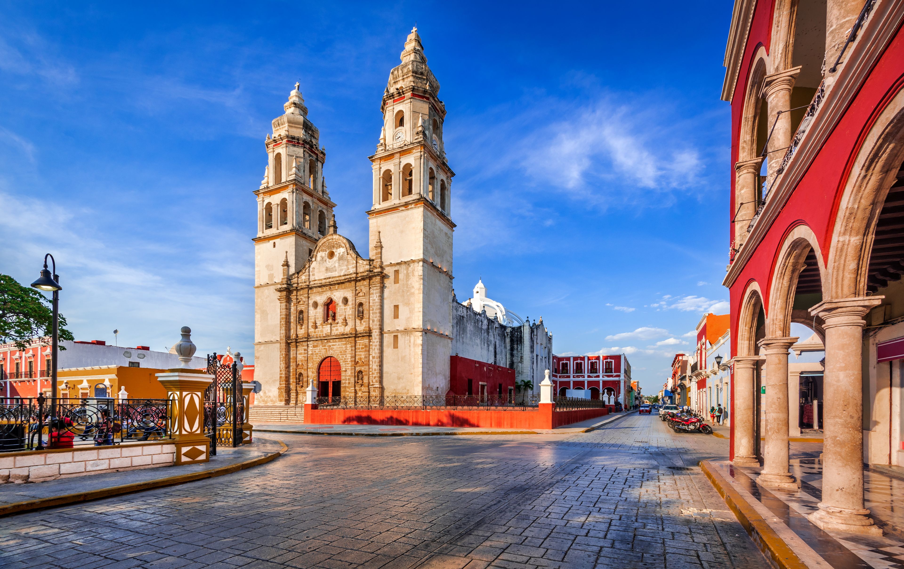 A historic church with two towers, a cobblestone street, and surrounding buildings.