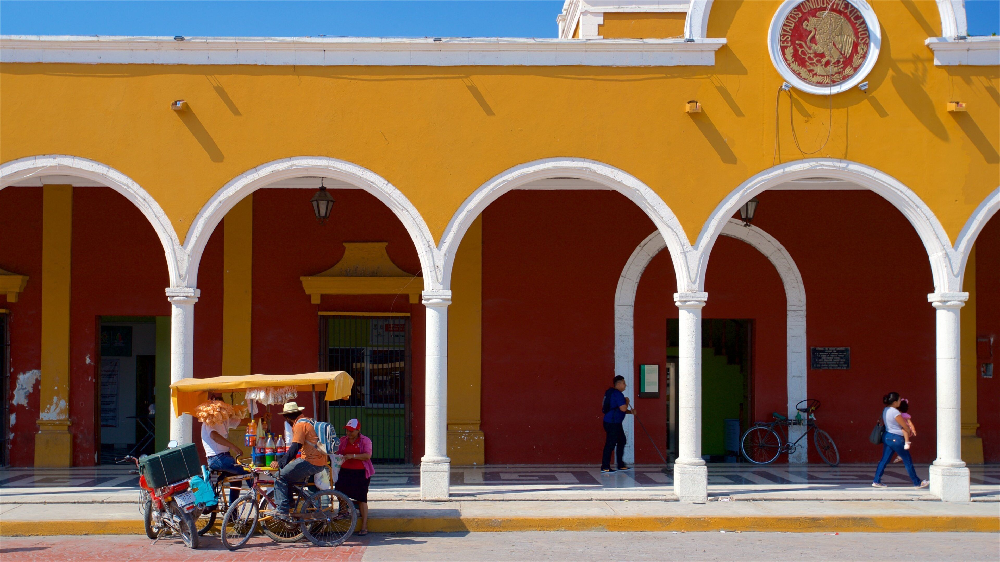 A yellow building with white arches and a coat of arms.