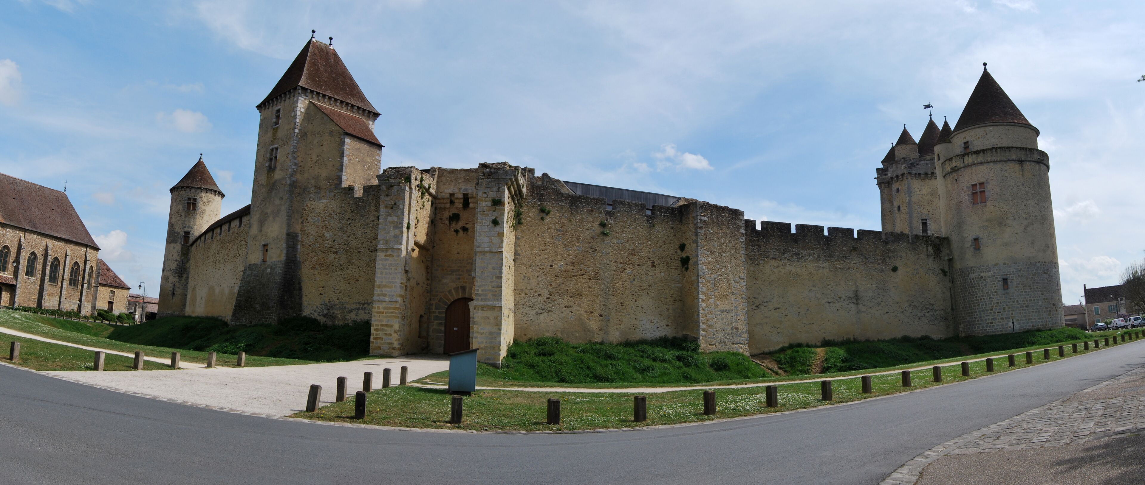 A historic castle with two prominent towers, a large central gate, and a surrounding wall.
