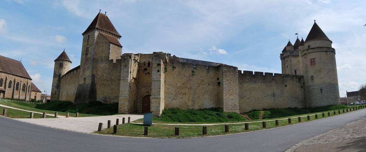 A historic castle with two prominent towers, a large central gate, and a surrounding wall.