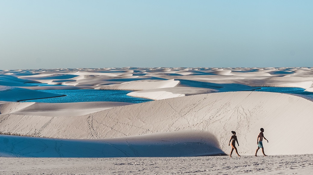 travel couple trek across giant sand dunes with lagoons in Lencois Maranhenses, one of the most stunning tourist attractions in North-East Brazil