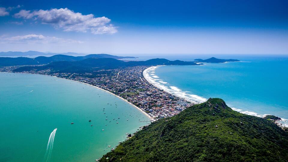 A coastal city with a long beach, dense urban area, and surrounding mountains.