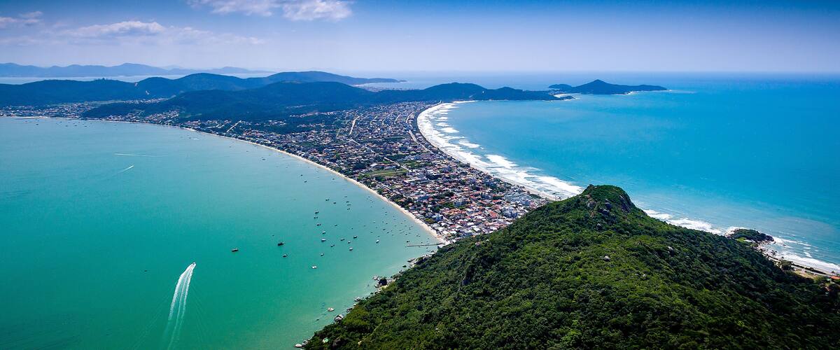 A coastal city with a long beach, dense urban area, and surrounding mountains.