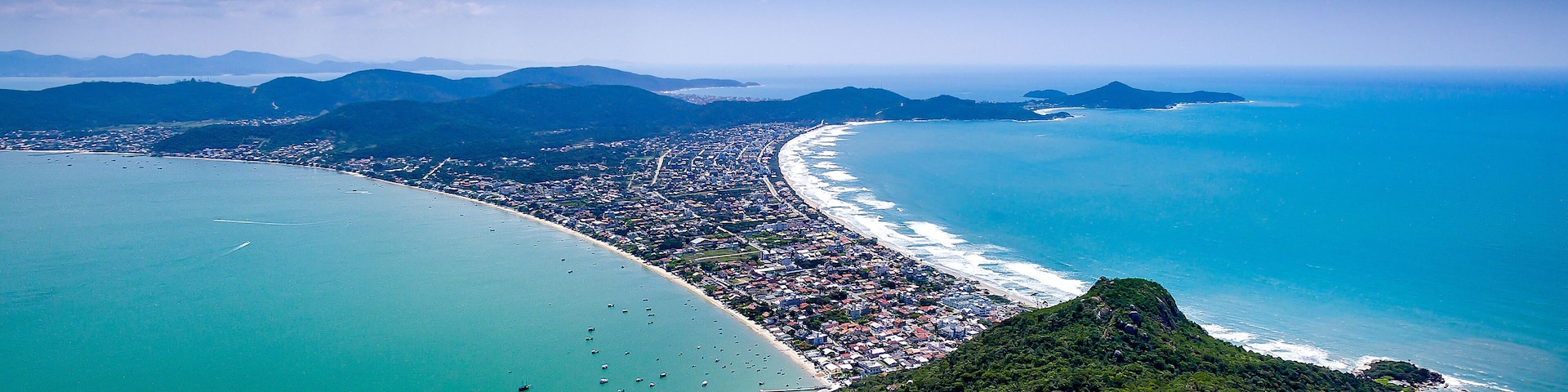 A coastal city with a long beach, dense urban area, and surrounding mountains.