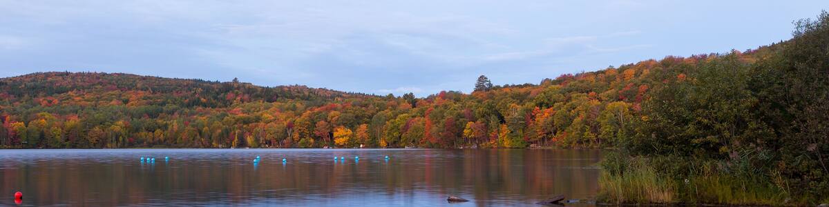 The Delage lake seen at dawn during the Fall season, with colourful wooded mountains in the background, Lac-Delage, Quebec, Canada