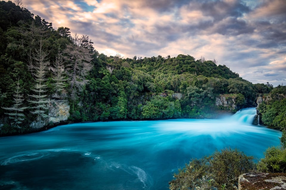 A river flowing through a forested gorge with a waterfall.