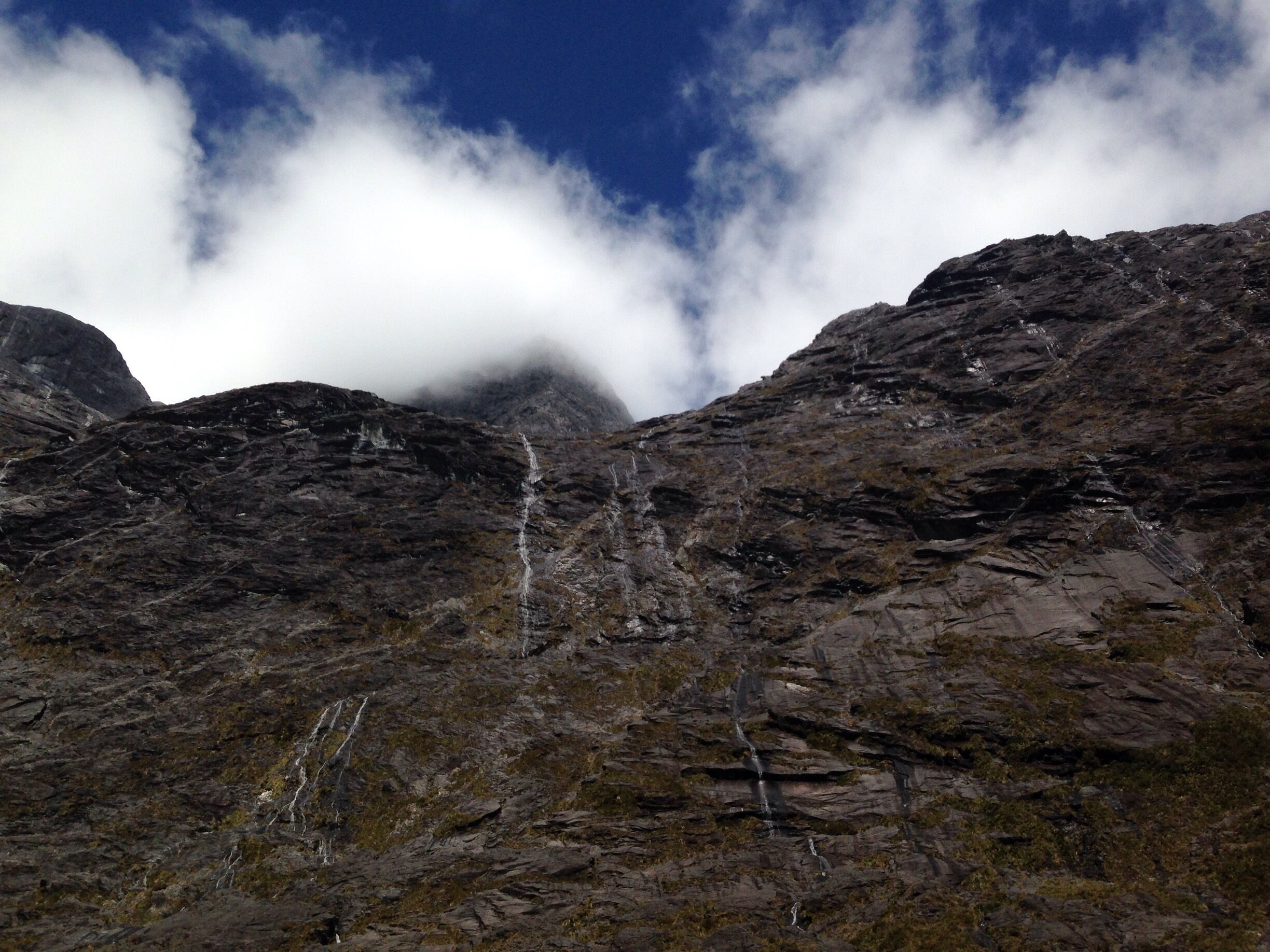 The beautiful mountains on the drive to Milford Sound, with waterfalls cascading down.