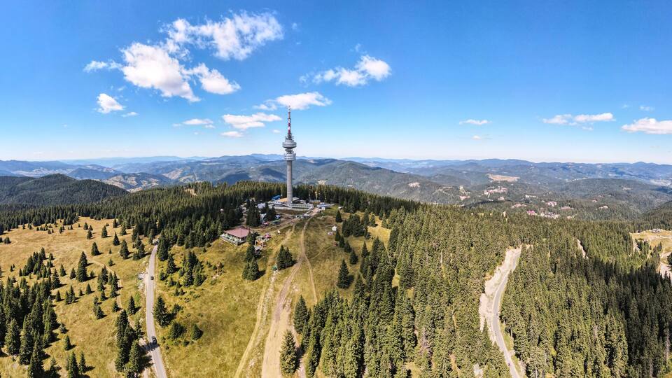 A mountain landscape with a tower, roads, and forested areas.