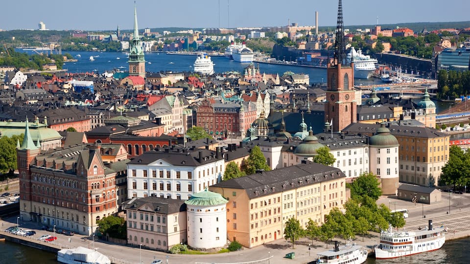 Un paisaje urbano con edificios históricos, una torre destacada y un río con barcos.